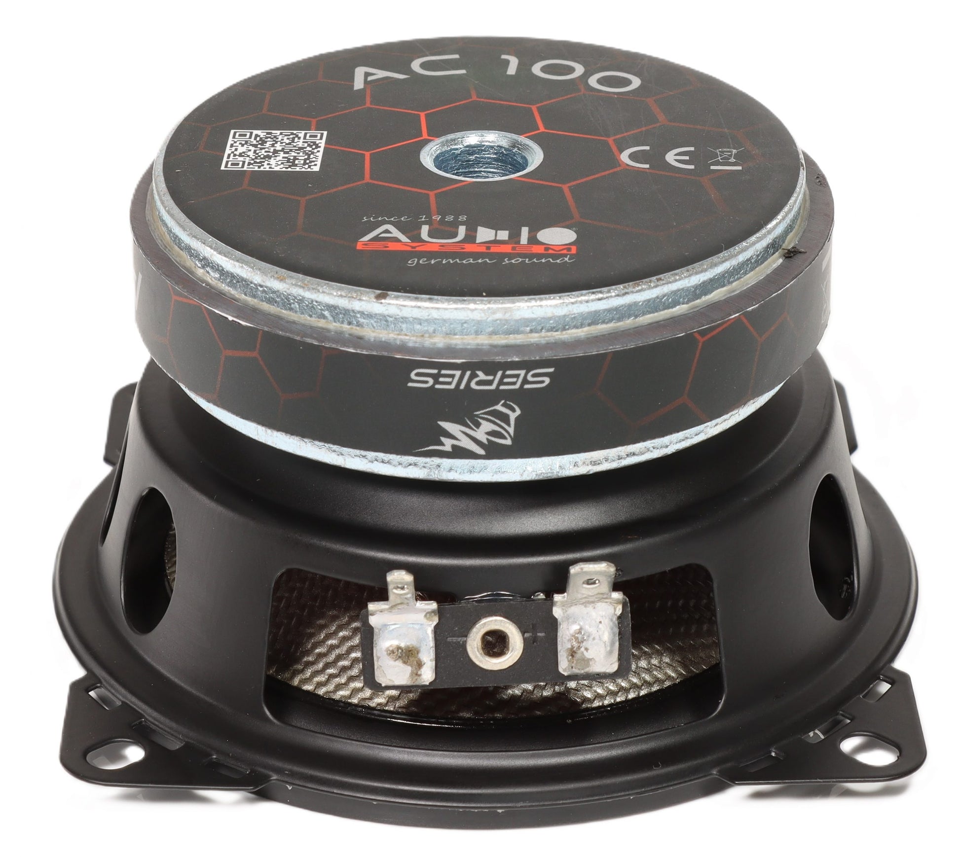 Eine Nahaufnahme eines Lautsprechers des Audiosystems CARBON 100, die den Metallrahmen, die Anschlüsse, die sechseckige Rückplatte und das Markenlogo hervorhebt.