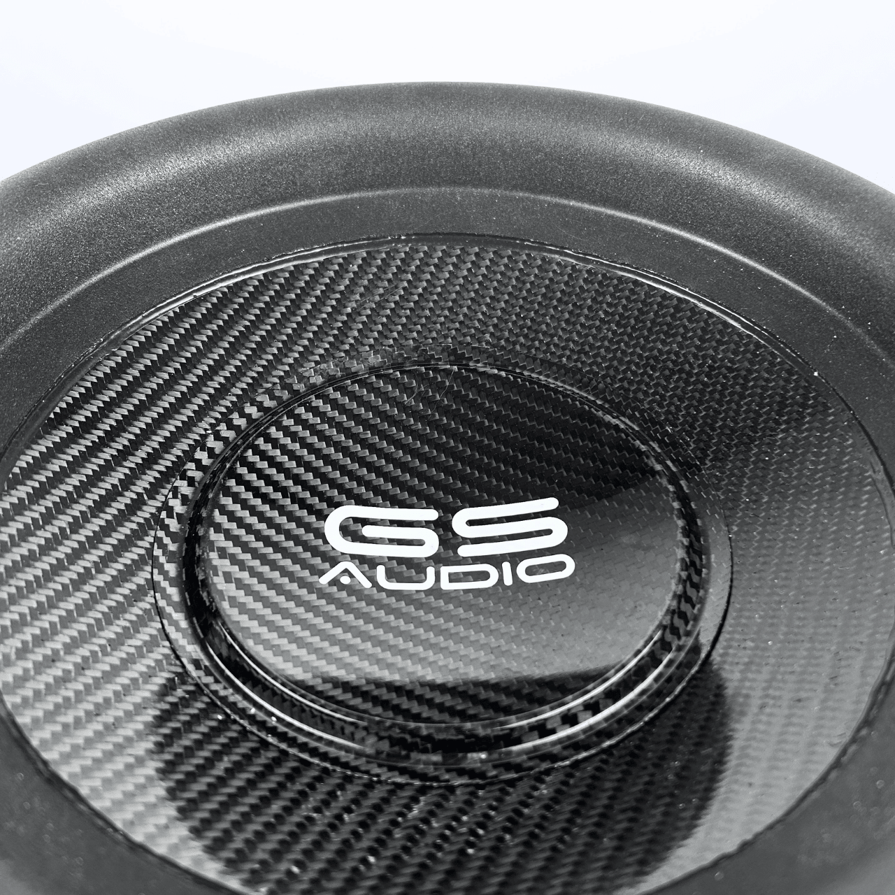 Gros plan sur un caisson de basses GS Audio Gold 10000 MK2 de 12 pouces, doté dune surface en fibre de carbone, dune membrane sandwich carbone-Kevlar et dun logo blanc ; conçu pour une puissance allant jusquà 10 000 W.