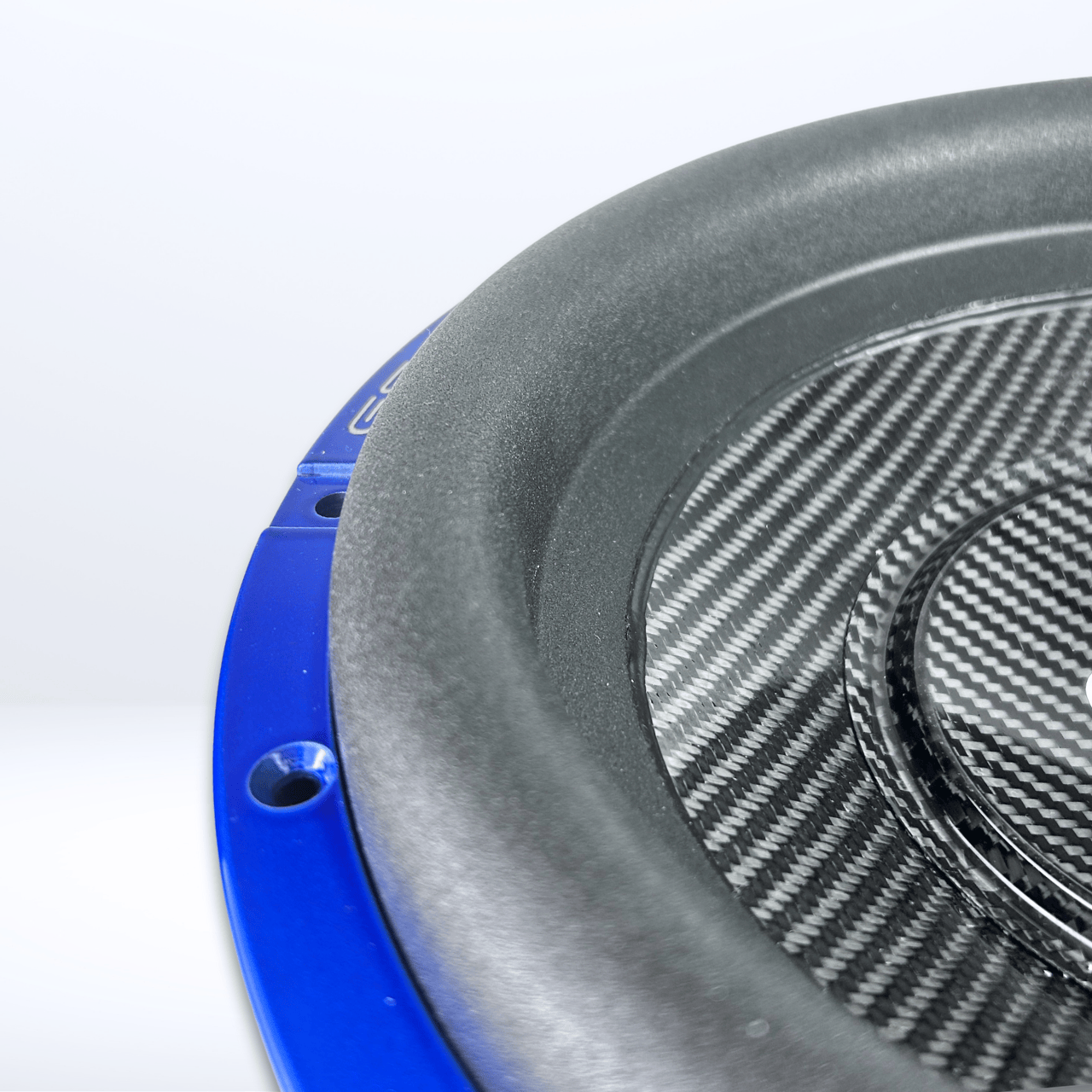 Nahaufnahme des GS Audio Gold 10000 MK2 12-Zoll-Subwoofers mit Carbon-Kevlar-Sandwich-Membran und Carbonfaser-Struktur vor einem hellen Hintergrund.