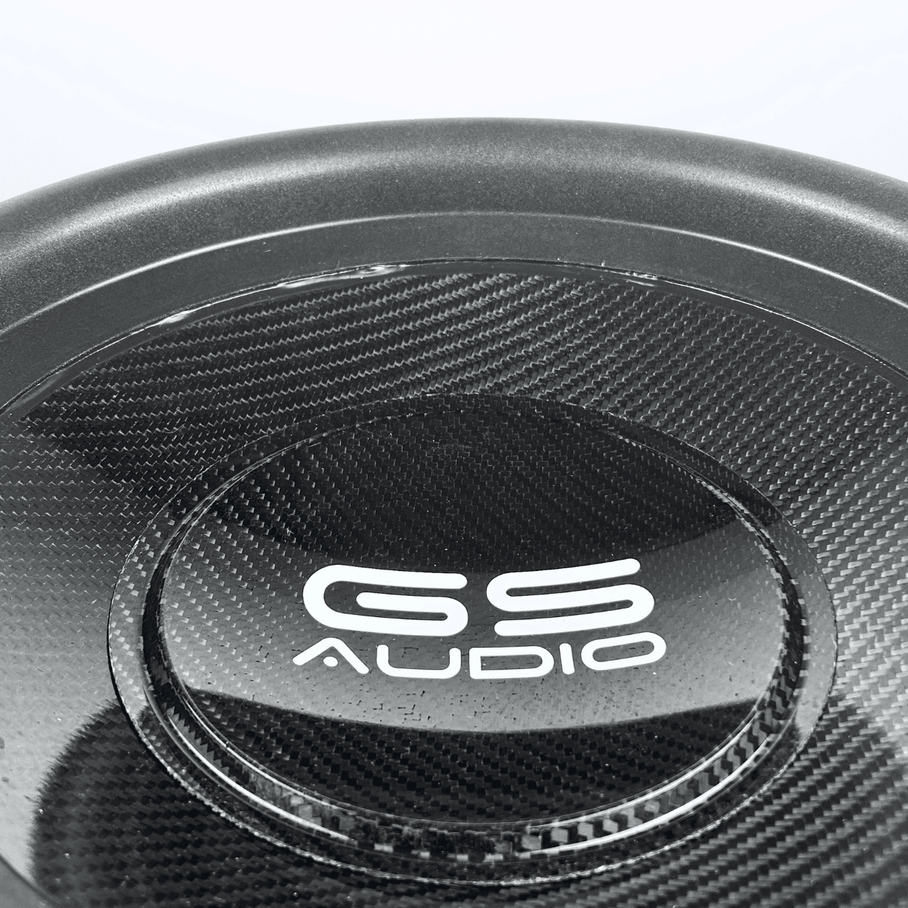 Nahaufnahme eines GS Audio Gold 10000 MK2 15-Zoll-Subwoofers mit Carbonfaser-Optik und dem in Weiß in der Mitte aufgedruckten Modellnamen.
