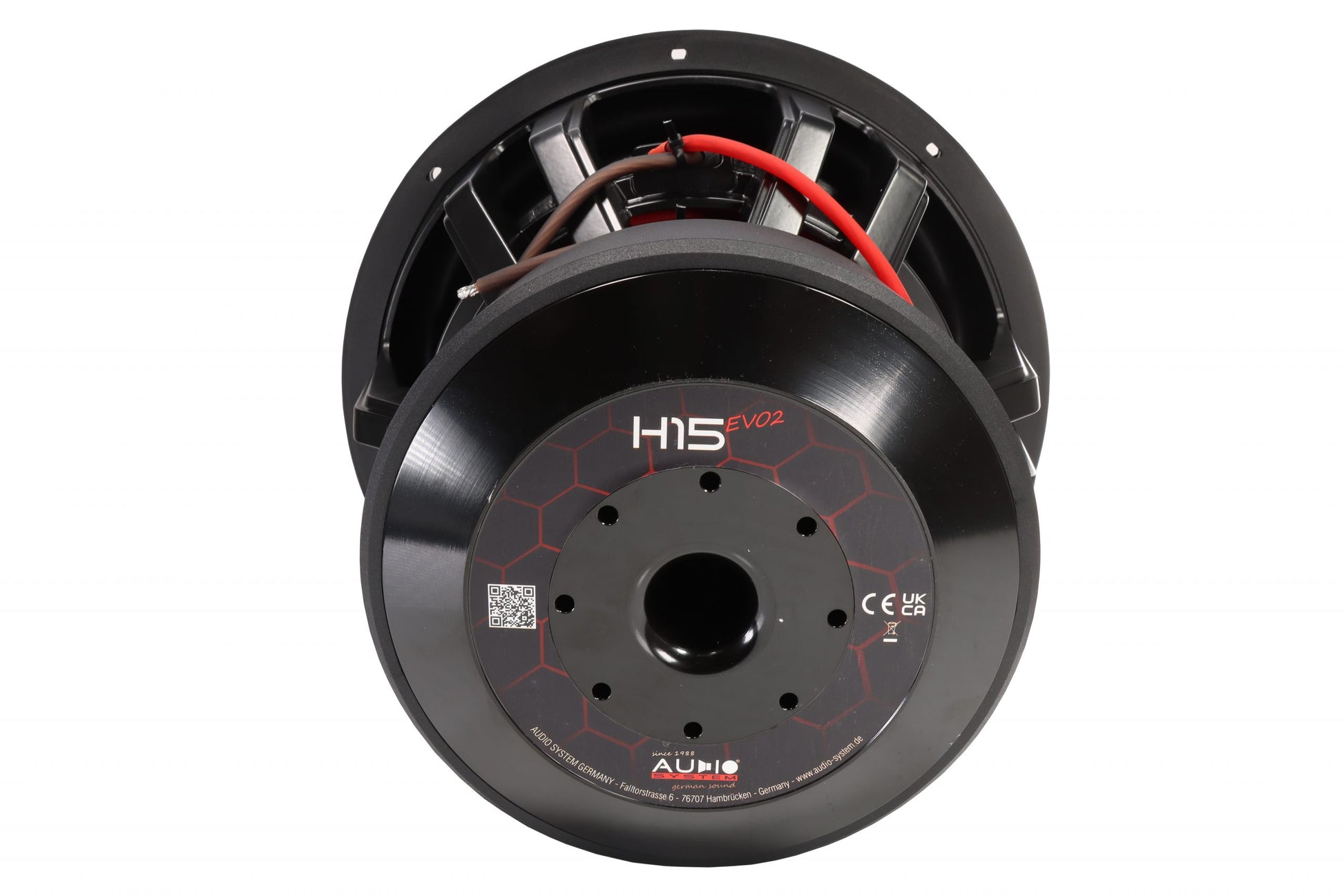 Un grand caisson de basses Audio System Helon H15 EVO2 SPL de la série H-EVO, de couleur noire, avec un câblage rouge ; la vue de dos montre le modèle et les caractéristiques techniques indiquées sur le socle.