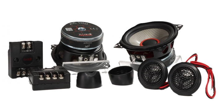 Le système audio CARBON 100 est un ensemble denceintes à 2 voies, composé de deux enceintes, de tweeters, de filtres, de grilles de protection, de câbles et de matériel de fixation, présenté sur un fond blanc.