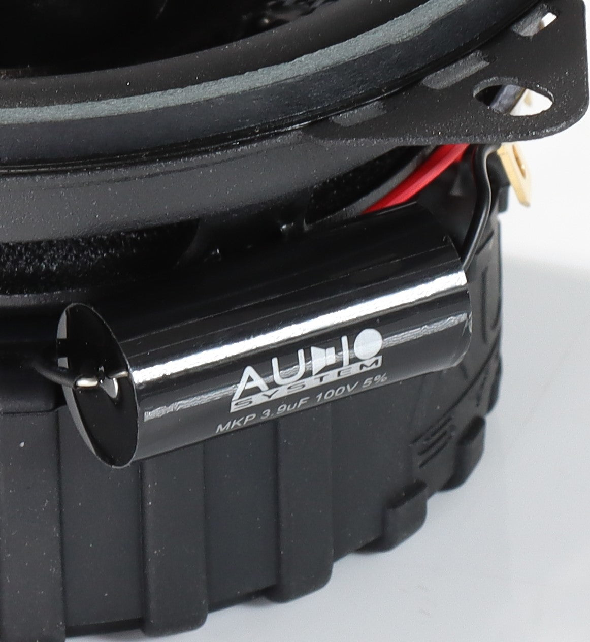 Un condensador AUDIO MKP negro en el sistema de audio RXC100 EVO3, conectado mediante cables visibles al altavoz de 4 pulgadas.