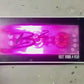 Un amplificatore rettangolare a 4 canali B2 Audio Riot 1800.4RGB, dotato di un display luminoso rosa-viola, mostra le scritte B340 e RIOT 1800.4 RGB in basso a destra; a sinistra è visibile una mano.