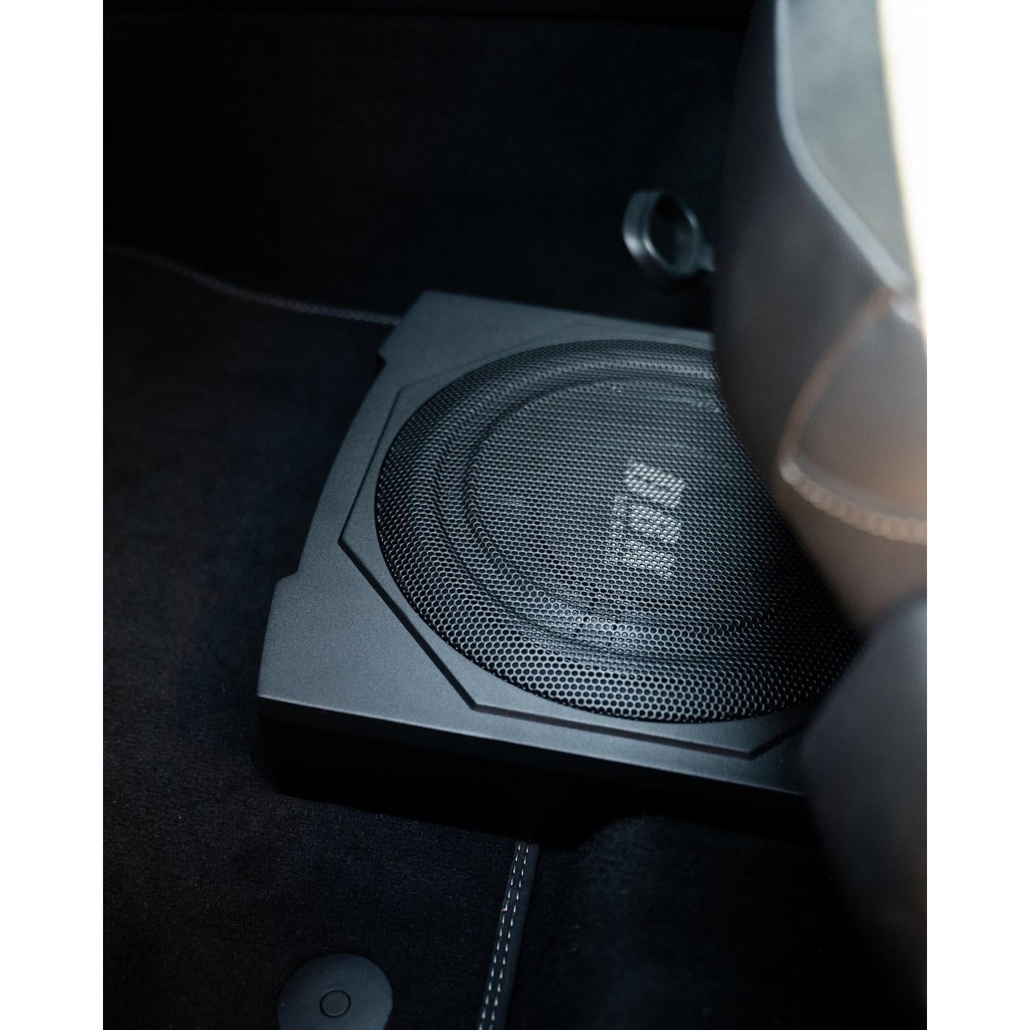 Edge Car Audio EDBX10A-E0 è un subwoofer nero ultrapiatto da 10 installato sotto il sedile dellauto, con la moquette e parte del sedile visibili.