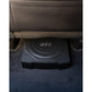 LEdge Car Audio EDBX10A-E0, un subwoofer nero da 10 Zoll con logo MBX, è posizionato sotto un sedile dellauto con design ultra-flaches tra la moquette scura e le cuciture a vista del sedile.