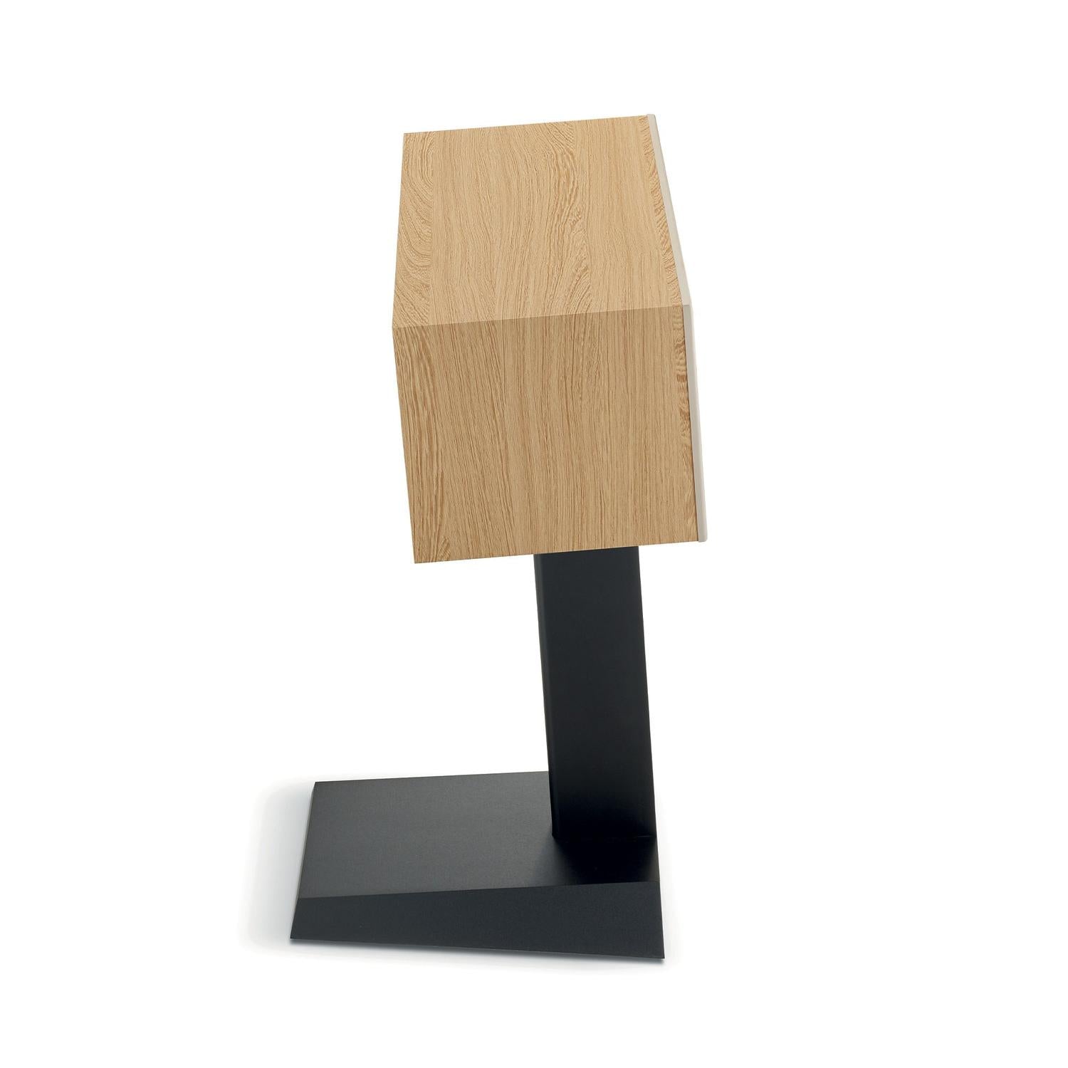 Der Focal Theva Center, ein moderner Holzlautsprecher mit rechteckigem Design, steht auf einem schwarzen Metallständer, von der Seite betrachtet vor einem weißen Hintergrund.