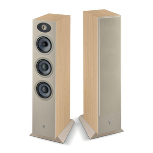Dos altavoces de suelo altos Focal Theva N°2 de 3 vías: uno muestra sus transductores de fibra de pizarra y el tweeter, el otro tiene un frontal de tela beige y una superficie de madera clara.