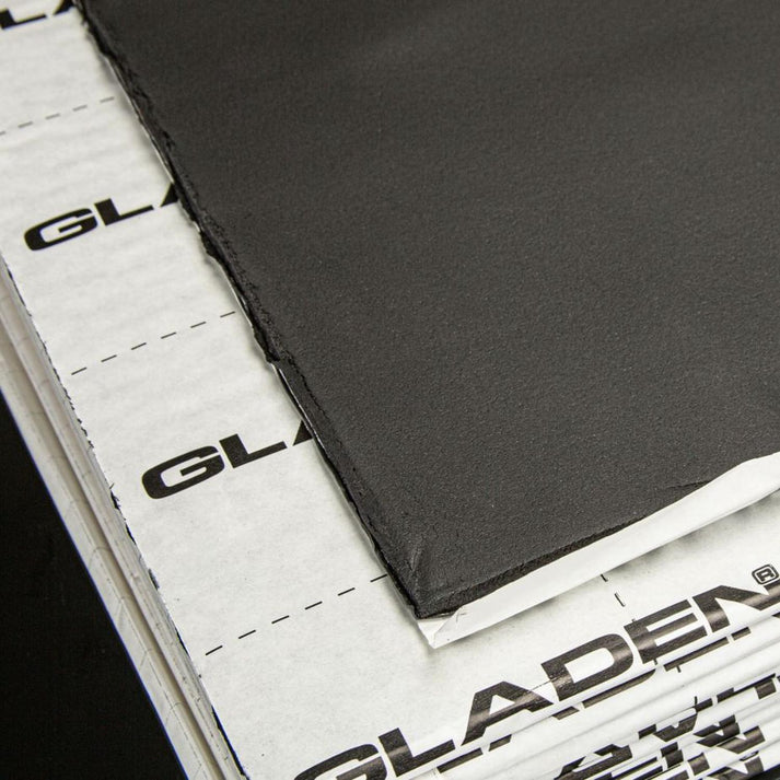 Gros plan sur les panneaux insonorisants noirs Gladen Aero Silent Pro, partiellement décollés pour laisser apparaître un support blanc portant la mention « GLADEN », garantissant une isolation de haute qualité.