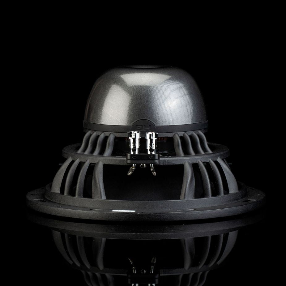 Un primer plano del subwoofer Aero 10 de Gladen Aerospace, con la parte trasera abovedada, detalles metálicos y conectores cilíndricos, sobre un fondo negro.