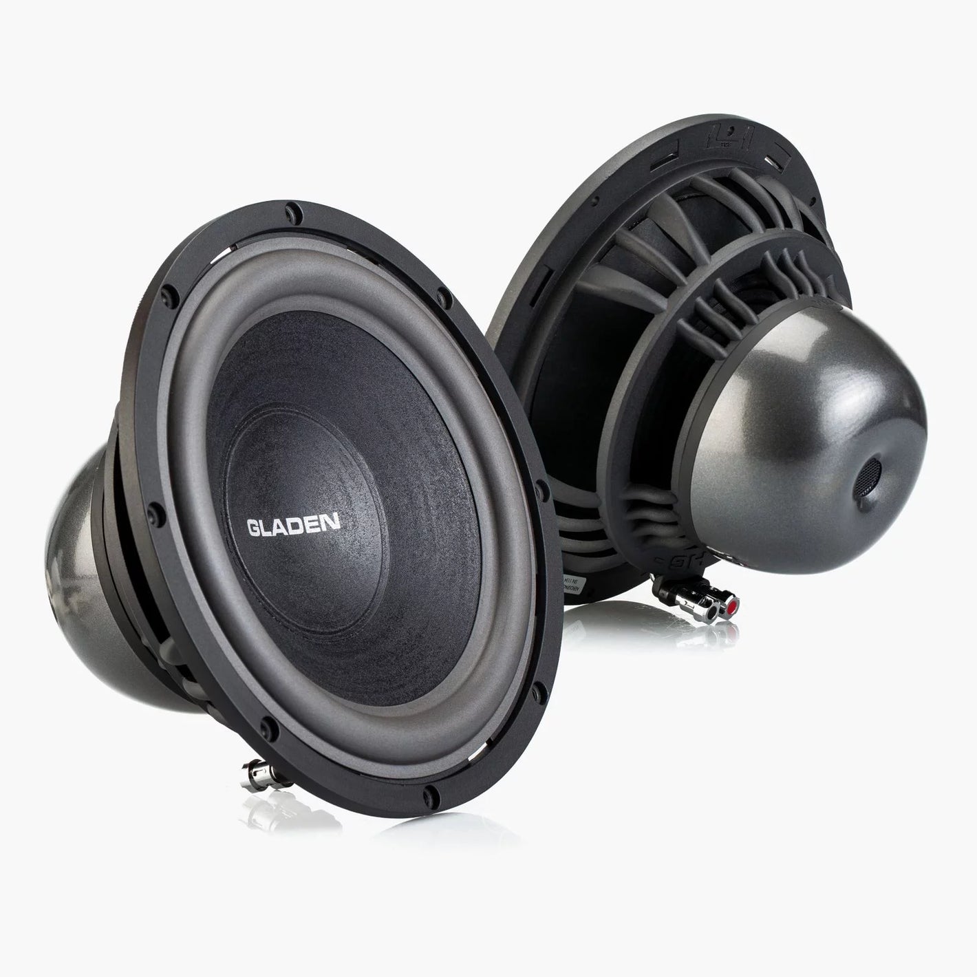 Se muestran dos subwoofers Aero 10 de Gladen Aerospace en color negro: uno con el cono a la vista y el otro con su imán metálico, ideales para los aficionados al «Auto Hifi».