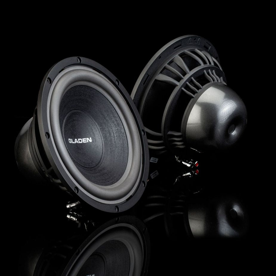 Due subwoofer neri Gladen Aerospace Aero 10 sono posizionati su una superficie riflettente, uno rivolto in avanti e l’altro all’indietro, mettendo in risalto il loro stile Auto Hifi di alta qualità.