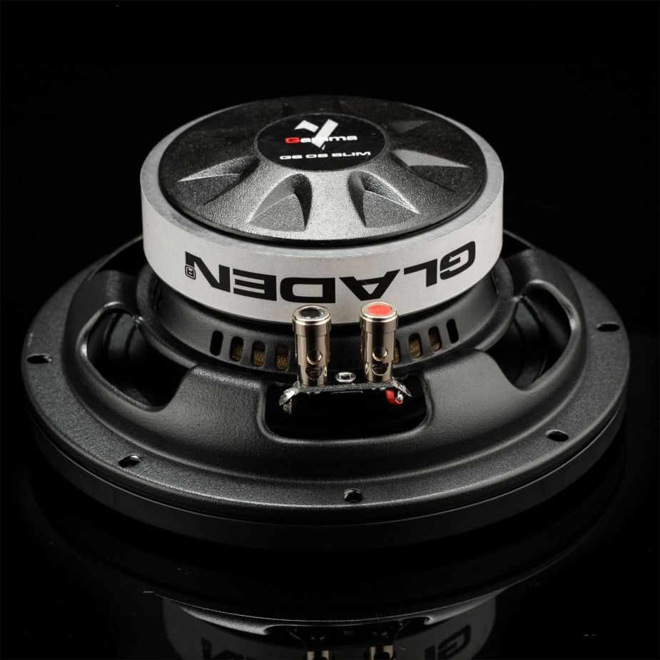 Un primer plano del subwoofer Gladen GS08-Slim, con conectores metálicos y el logotipo de la marca, sobre un elegante fondo negro.
