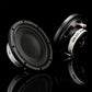 Se muestran dos subwoofers Gladen GS08-Slim de 8 pulgadas, en negro y plateado, con rejillas de malla, sobre una superficie negra brillante que refleja su imagen.