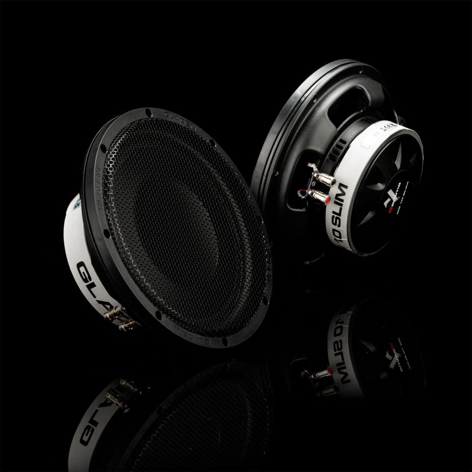 Two black and white Gladen GS10-Slim subwoofers sit on a glossy black surface, one facing forward to showcase their powerful sound.