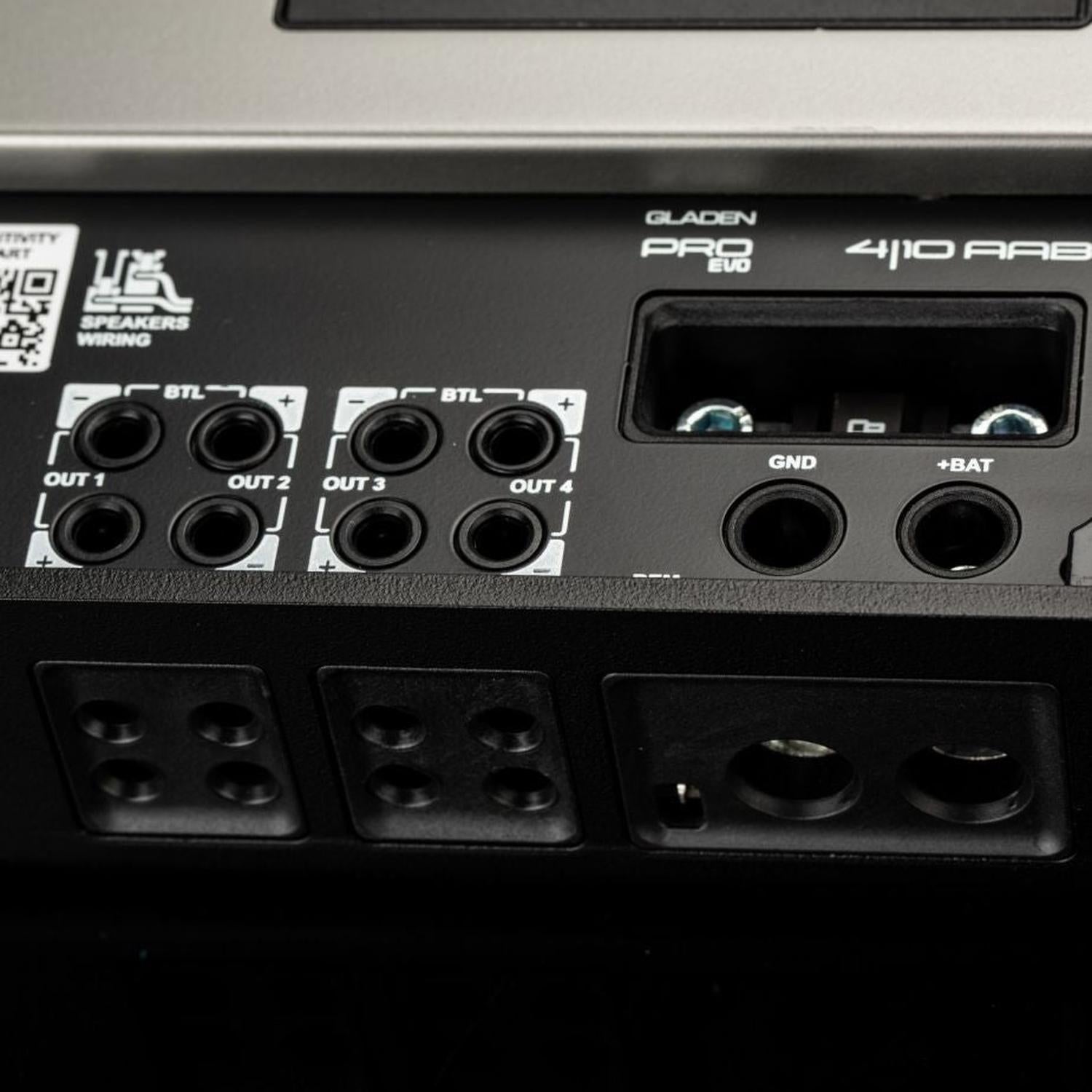 Primo piano del retro dellamplificatore «Gladen Mosconi Pro 4|10-AAB EVO» con uscite contrassegnate, terminali per altoparlanti e connettori GND e +BAT per il vostro impianto audio per auto.