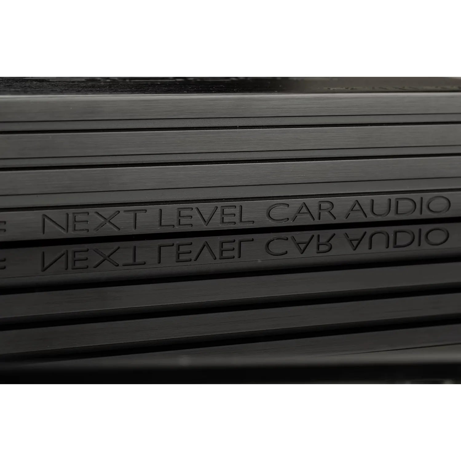 Gros plan sur lamplificateur de classe D Gladen Rcore 1|1200, sur lequel est gravée linscription « NEXT LEVEL CAR AUDIO », et son reflet sur la surface métallique.