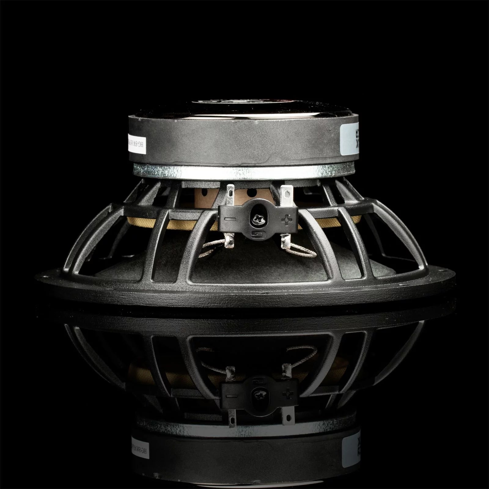 On voit ici un haut-parleur dautoradio Gladen Sigma 165 avec cadre métallique, photographié de profil sur une surface noire brillante.