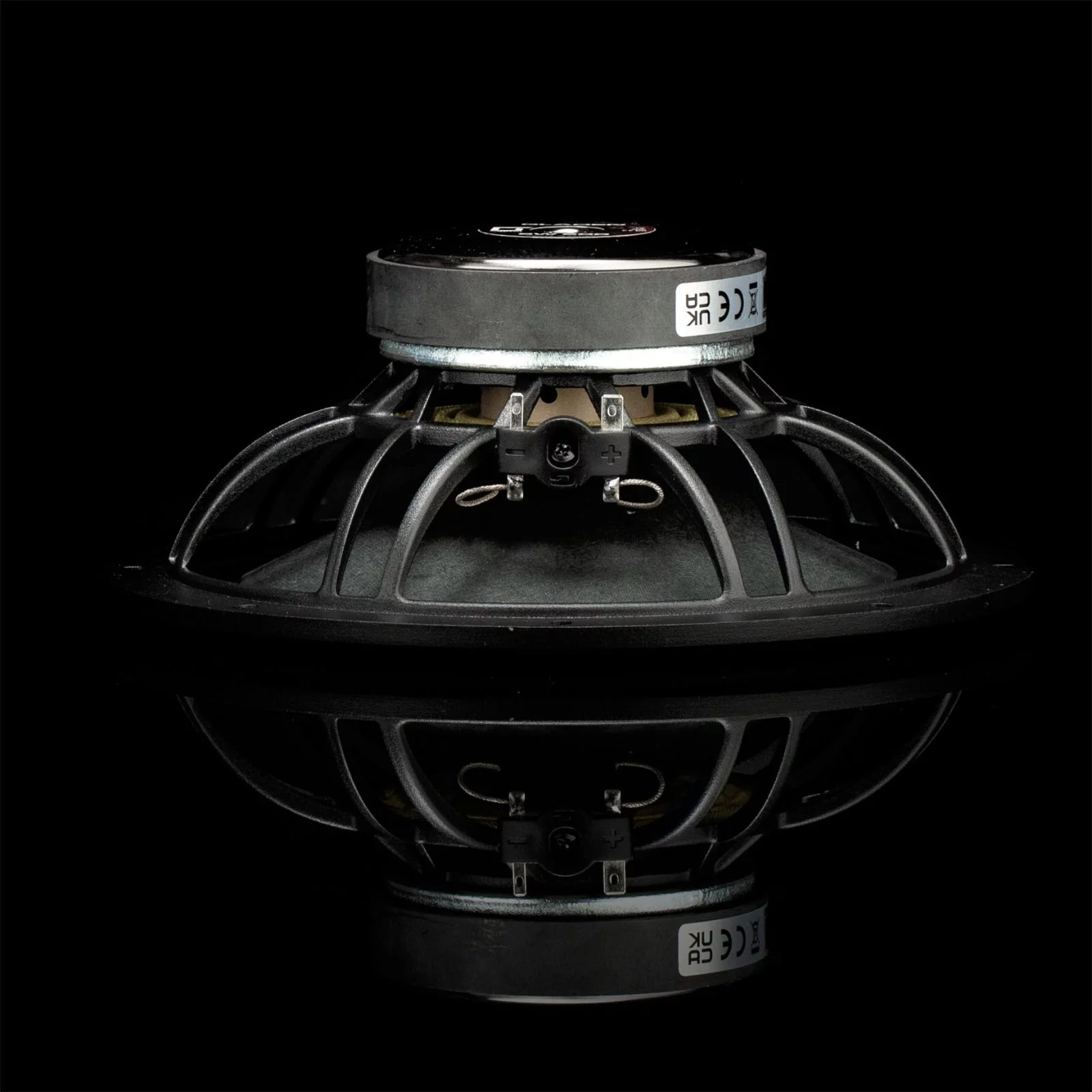 A Gladen Sigma 200 speaker driver for Car Audio, black with metal frame and terminals, is side-viewed and reflected on a shiny black surface.