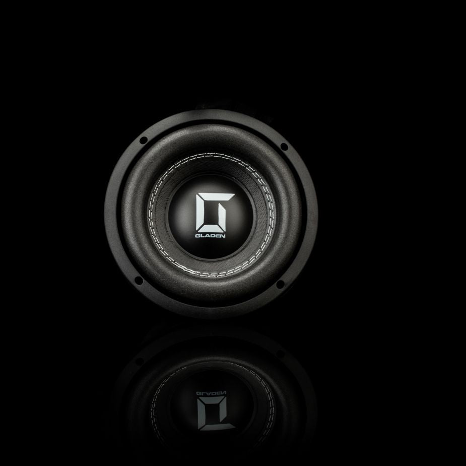 El Gladen Sigma SSW065, un subwoofer negro con el logotipo de Gladen en plata, ofrece unos graves precisos y aparece en una imagen sobre un fondo negro con un sutil reflejo.