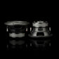 Dos subwoofers negros de 8 pulgadas del modelo Gladen Sigma SSW08, colocados sobre una superficie reflectante —que se muestran aquí desde delante y desde atrás—, ponen de manifiesto el elegante diseño del sistema de audio para coche.
