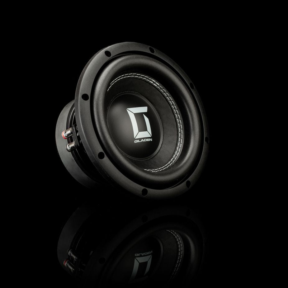 Il Gladen Sigma SSW08, un subwoofer nero da 8 pollici con un logo argentato sulla membrana, è raffigurato su uno sfondo nero con un leggero riflesso.
