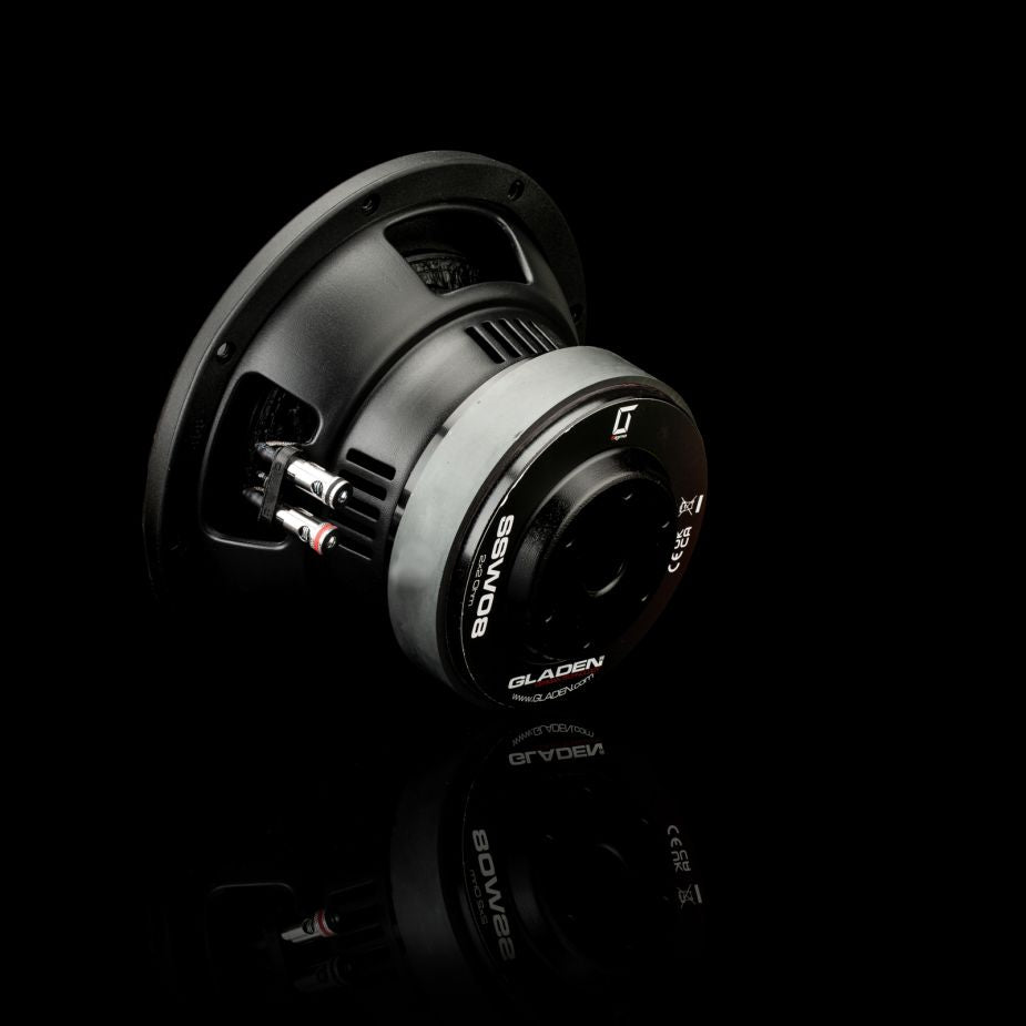 Il subwoofer Gladen Sigma SSW08 è raffigurato inclinato su una superficie nera lucida, che ne mette in risalto il design nero e argento e il marchio ben visibile: ideale per impianti audio per auto di fascia alta.