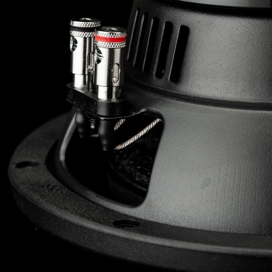 Primo piano di due connettori argentati e cavi su un subwoofer Gladen Sigma SSW08 da 8 pollici, su uno sfondo scuro.