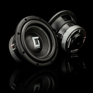 Deux caissons de basses Gladen Sigma SSW08 noirs, l’un posé à la verticale et l’autre incliné sur une surface brillante — parfaits pour les systèmes audio automobiles haut de gamme.