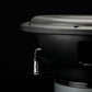 Primer plano de un subwoofer Gladen Sigma SSW10 sobre un fondo oscuro, en el que se aprecian su puerto de conexión y el cono texturizado del altavoz.