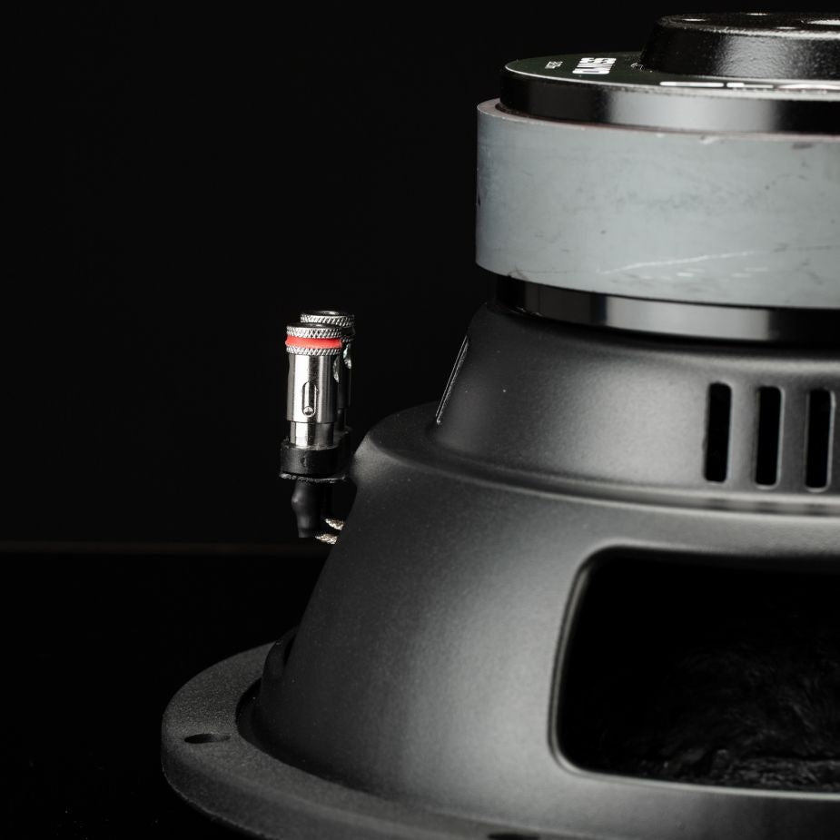 Un primo piano del subwoofer Gladen Sigma SSW10 ne mostra i collegamenti e i magneti: ideale per impianti audio per auto di alta qualità.