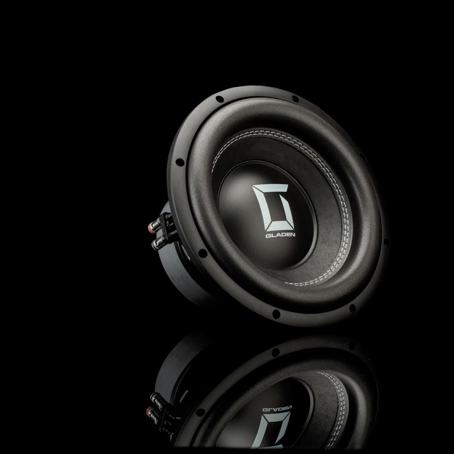 Un subwoofer Gladen Sigma SSW10 nero con logo argentato è posizionato su una superficie riflettente, ideale per impianti audio per auto di alta gamma.