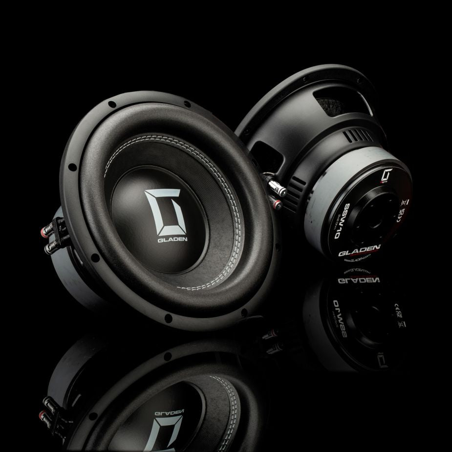 Due subwoofer Gladen Sigma SSW10 neri sono ripresi su una superficie lucida: uno è rivolto in avanti, l’altro mostra il lato e il retro.