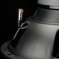 Primer plano de un terminal del subwoofer Gladen Sigma SSW12 con un conector de cable negro con una banda roja, sobre un fondo oscuro.