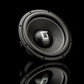 Un subwoofer Gladen Sigma SSW12 con acabado negro metalizado se exhibe sobre una superficie negra brillante, lo que resalta su diseño redondeado y su logotipo.