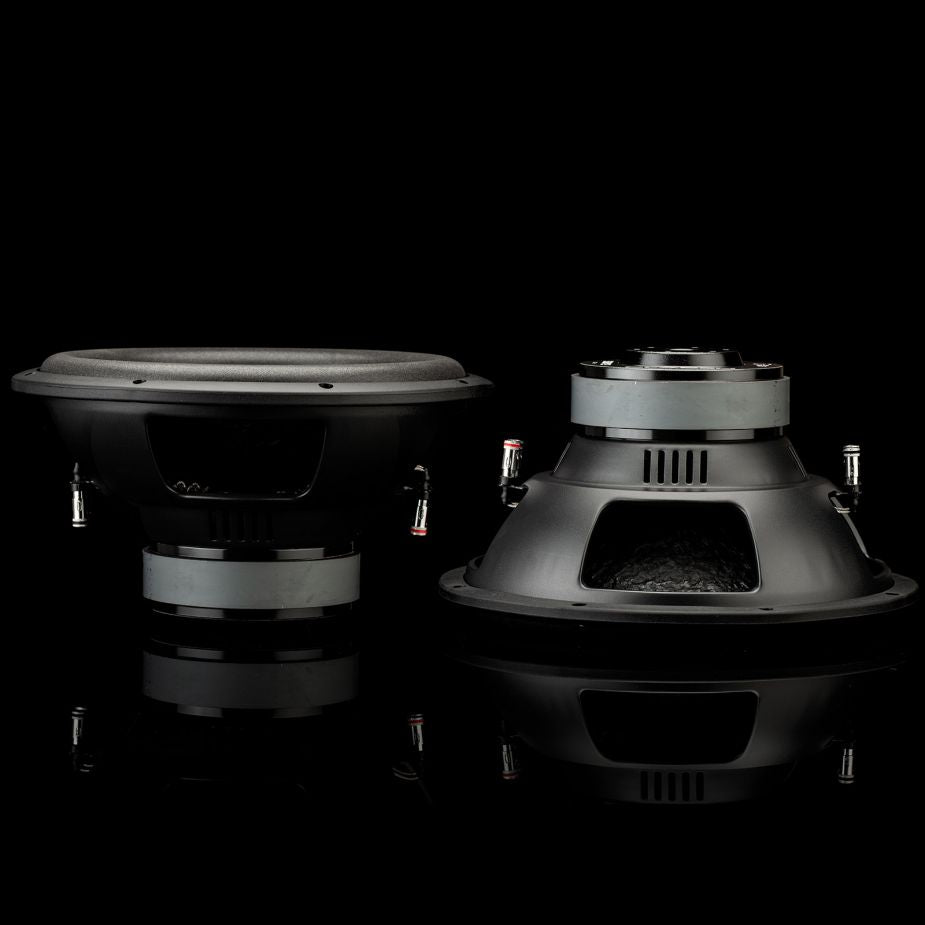Due subwoofer Gladen Sigma SSW12 – uno rivolto in avanti, l’altro inclinato – si riflettono su una superficie lucida davanti a un elegante sfondo nero.