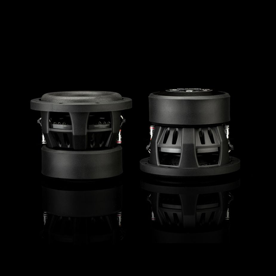 En la imagen aparecen dos subwoofers Gladen Sigma SSWX065 negros de 6 pulgadas, diseñados para su instalación en vehículos, sobre un fondo negro liso con un ligero reflejo en la parte inferior.