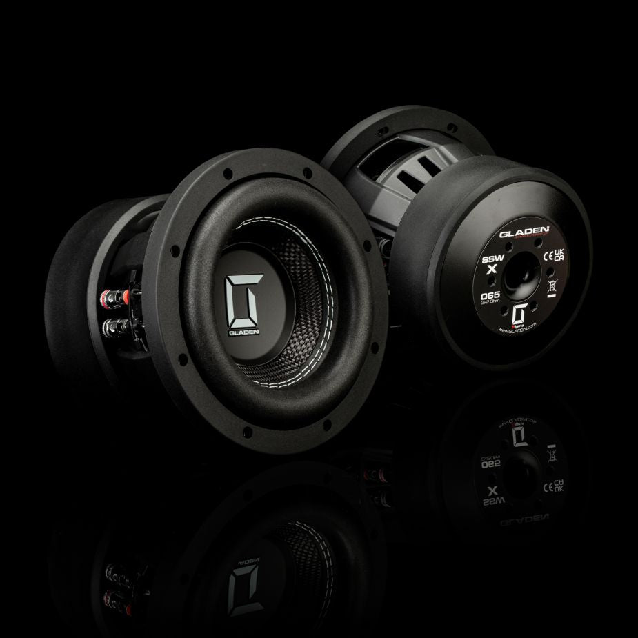 Due subwoofer Gladen Sigma SSWX065, ripresi frontalmente e posteriormente su una superficie riflettente, mostrano i loghi, i terminali di collegamento e i dettagli del modello, garantendo un’eccellente riproduzione dei bassi.