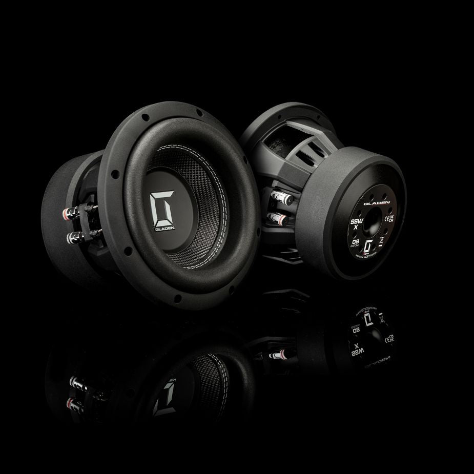 Se muestran dos subwoofers para coche Gladen Sigma SSWX08 sobre una superficie negra reflectante, con el logotipo visible: uno está orientado hacia delante y el otro muestra su parte trasera.