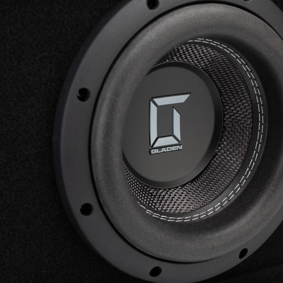 Un primer plano del Gladen Sigma SSWX08VB, un subwoofer de 8 pulgadas, muestra las costuras visibles y un centro con textura de fibra de carbono.
