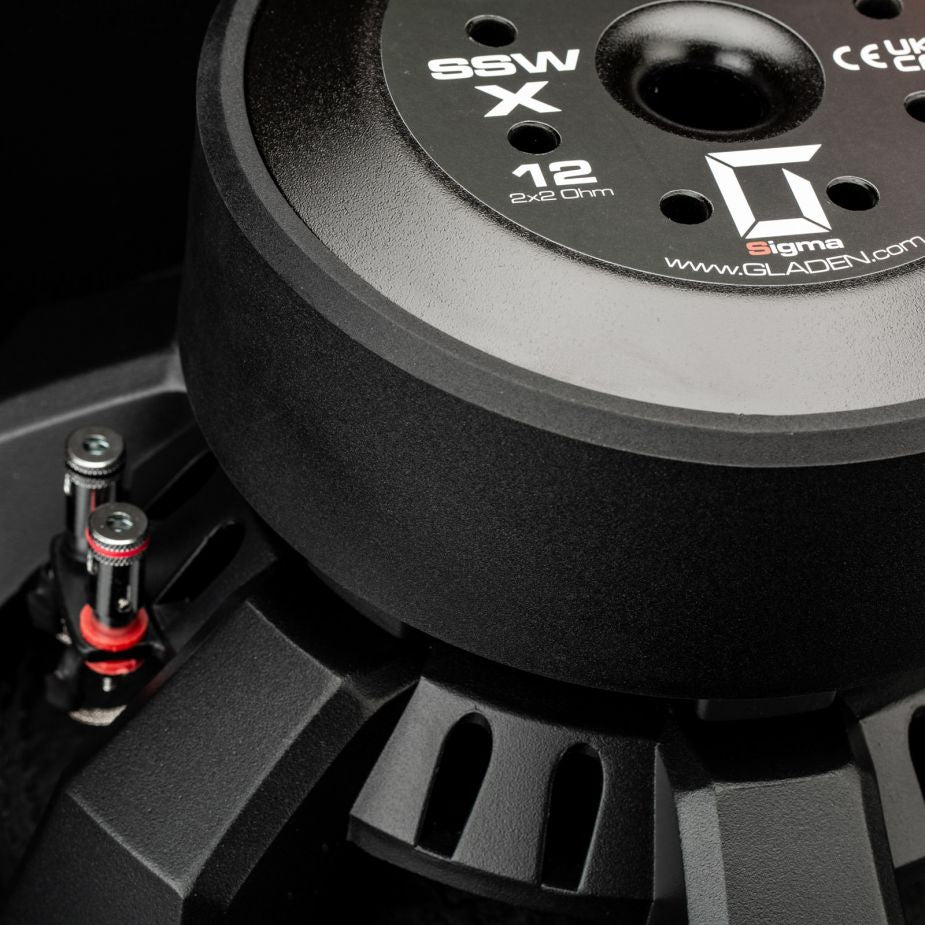 Primer plano del subwoofer Gladen Sigma SSWx12, en el que se aprecian los terminales de conexión y la etiqueta con las especificaciones técnicas.
