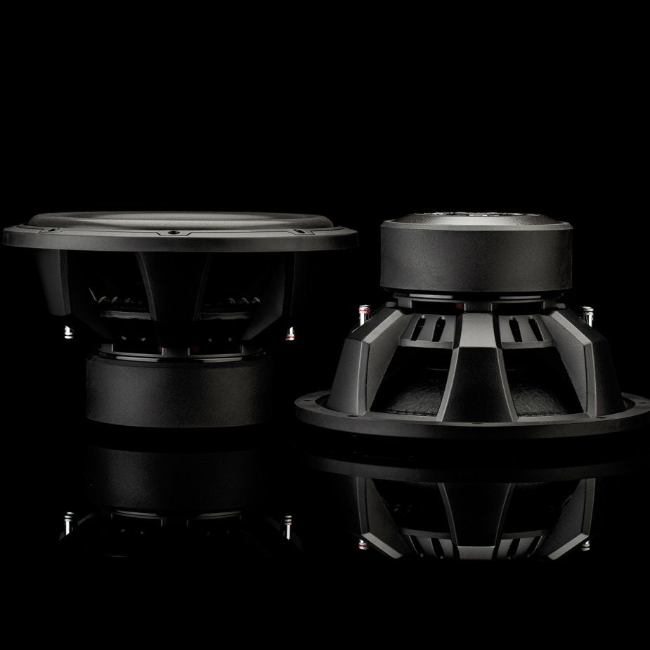 Su una superficie riflettente si vedono due subwoofer Gladen Sigma SSWx12, uno dei quali è rivolto in avanti, mentre l’altro mostra il lato e il retro.