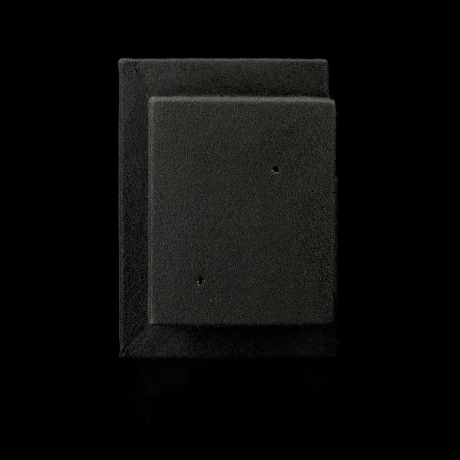 Due rettangoli neri in schiuma, uno dei quali più piccolo e posizionato al centro dellaltro, ricordano una parte del subwoofer «Gladen Subbox-Buz.2» con piccoli fori, raffigurati su uno sfondo nero.