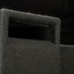 Primo piano di un incavo rettangolare per la maniglia nel cabinet del subwoofer “Gladen Subbox-Buz.2”, di colore grigio scuro e con superficie strutturata, su sfondo nero.
