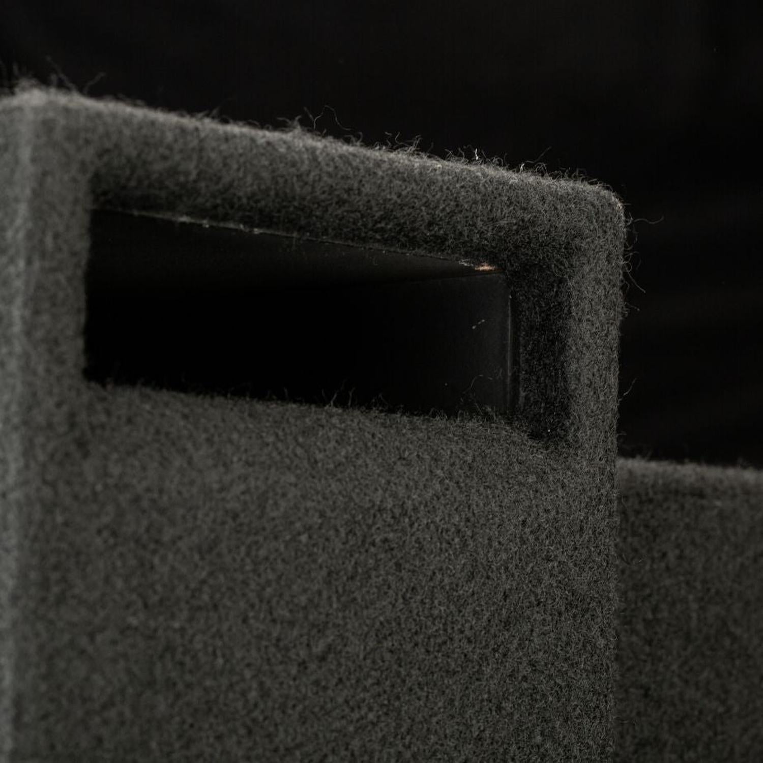 Primo piano di un incavo rettangolare per la maniglia nel cabinet del subwoofer “Gladen Subbox-Buz.2”, di colore grigio scuro e con superficie strutturata, su sfondo nero.