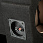 Primo piano del subwoofer nero rivestito in moquette “Gladen Subbox-Buz.2”, dotato di due connettori – uno rosso e uno nero – su una mascherina incassata.