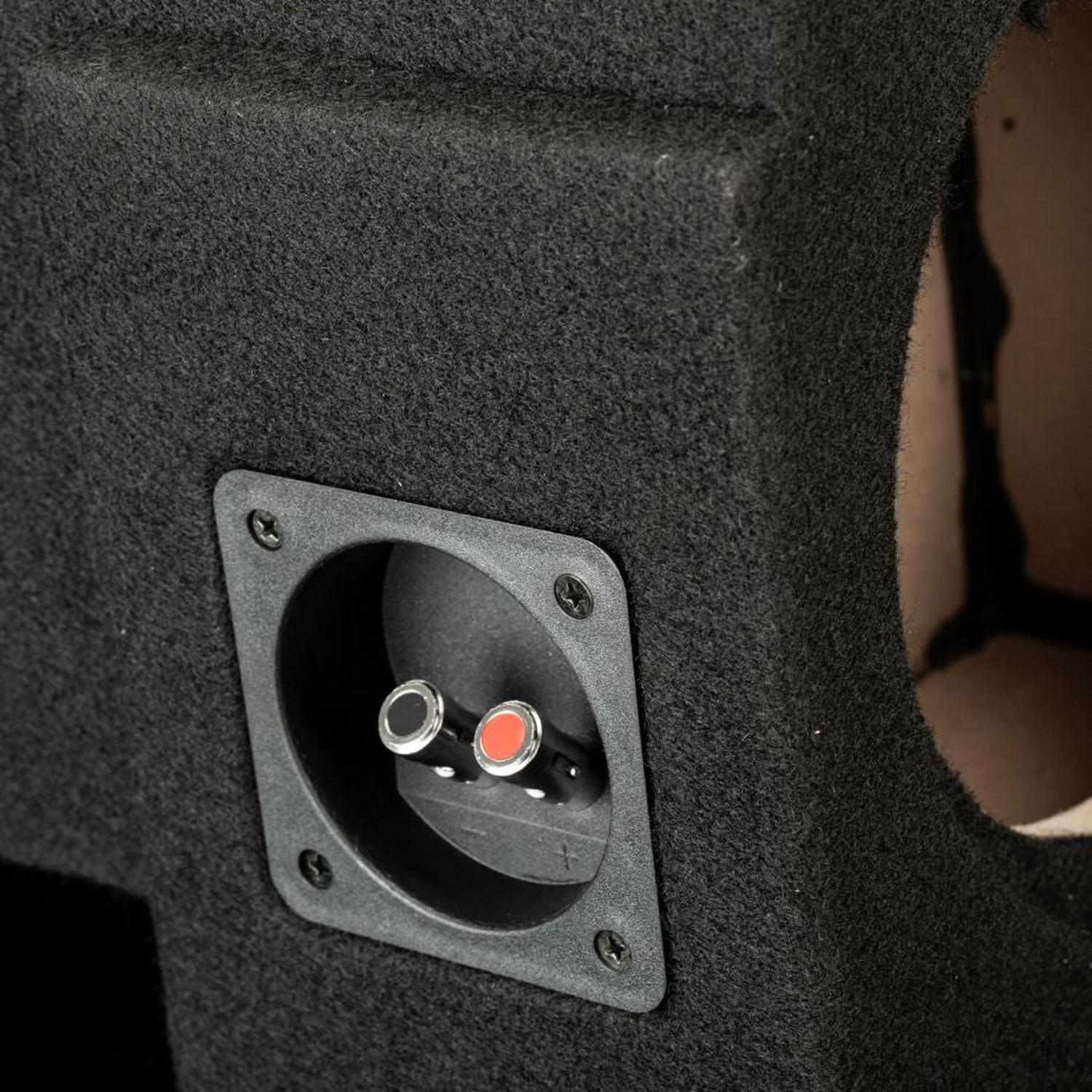 Primo piano del subwoofer nero rivestito in moquette “Gladen Subbox-Buz.2”, dotato di due connettori – uno rosso e uno nero – su una mascherina incassata.