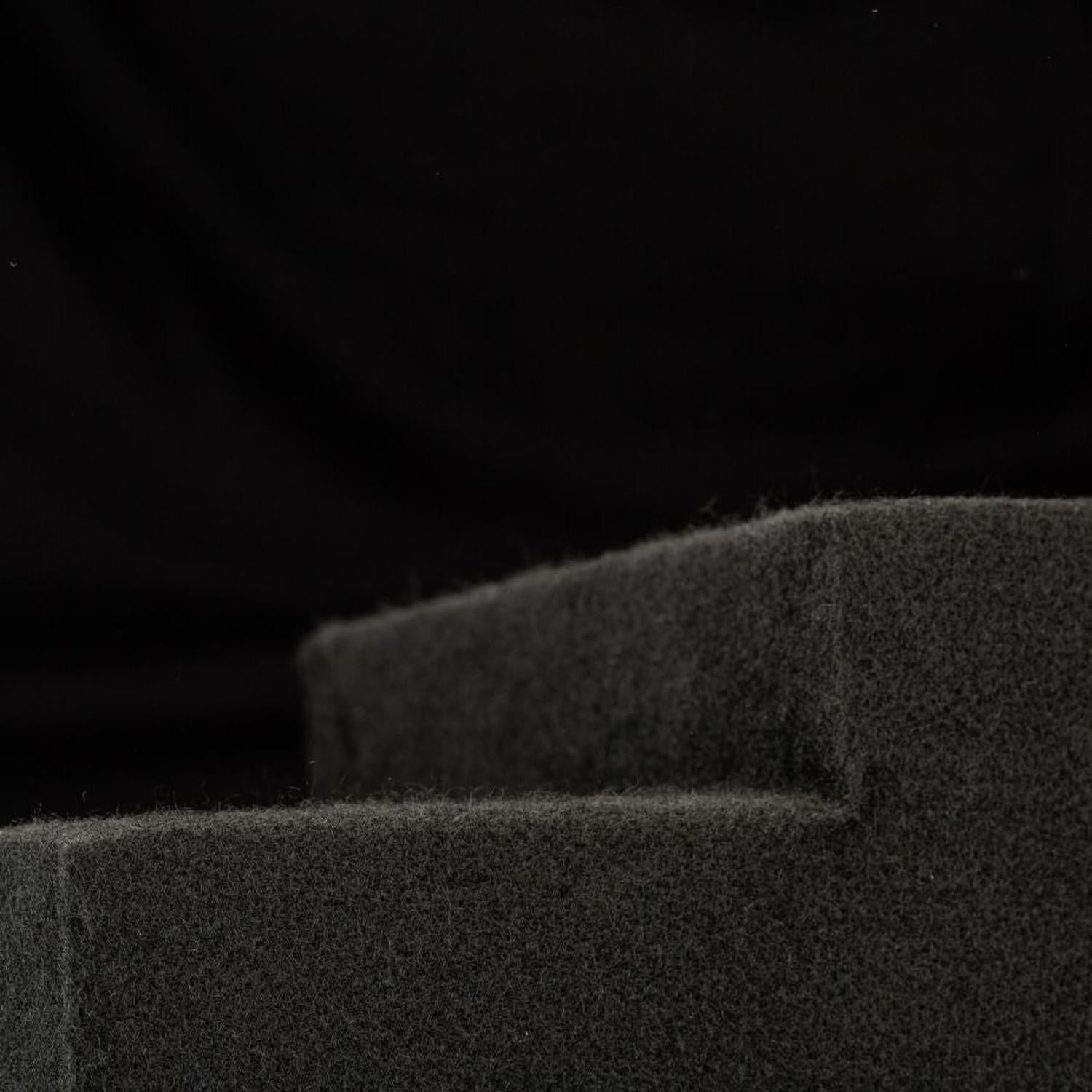 Un primo piano di schiuma grigio scuro con bordo smussato, su cui è visibile il “Subbox-Buz.2” di Gladen per il subwoofer della VW ID.Buzz, su sfondo nero.