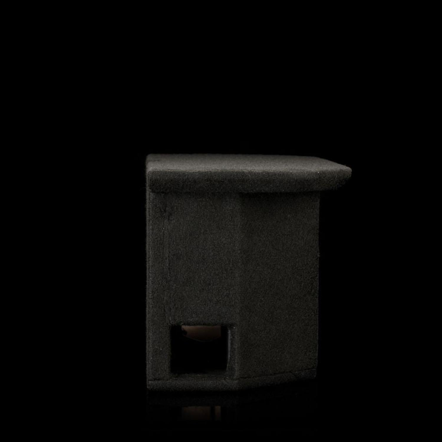 Su uno sfondo nero si vede un Gladen Subbox-EV compatto, di colore grigio scuro, con la parte superiore piatta e un’apertura quadrata nella parte inferiore.