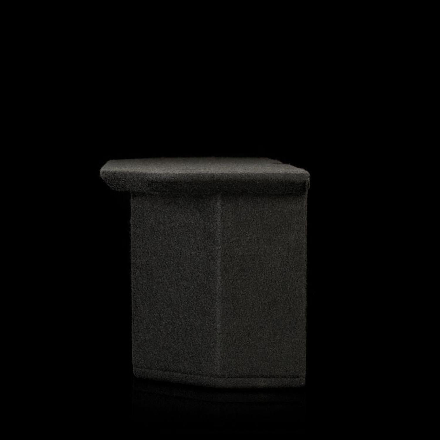 Un Gladen Subbox-EV rettangolare, di colore grigio scuro, è appoggiato su uno sfondo nero, con il bordo superiore leggermente sporgente.